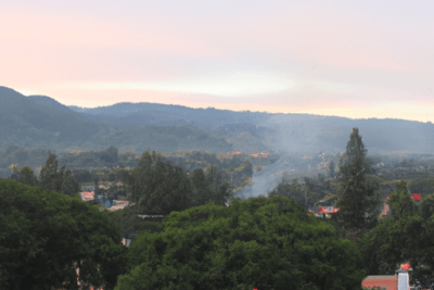 Panorámica de un pueblo entre montañas al atardecer con humo sobre los tejados y estando yo una tarde una experiencia personal que cambio mi vida